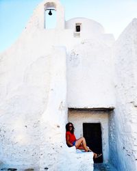 Full length of woman sitting by historical building