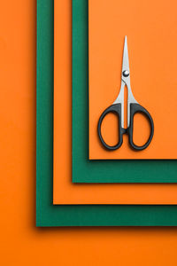 Scissors on green and orange cardboard background