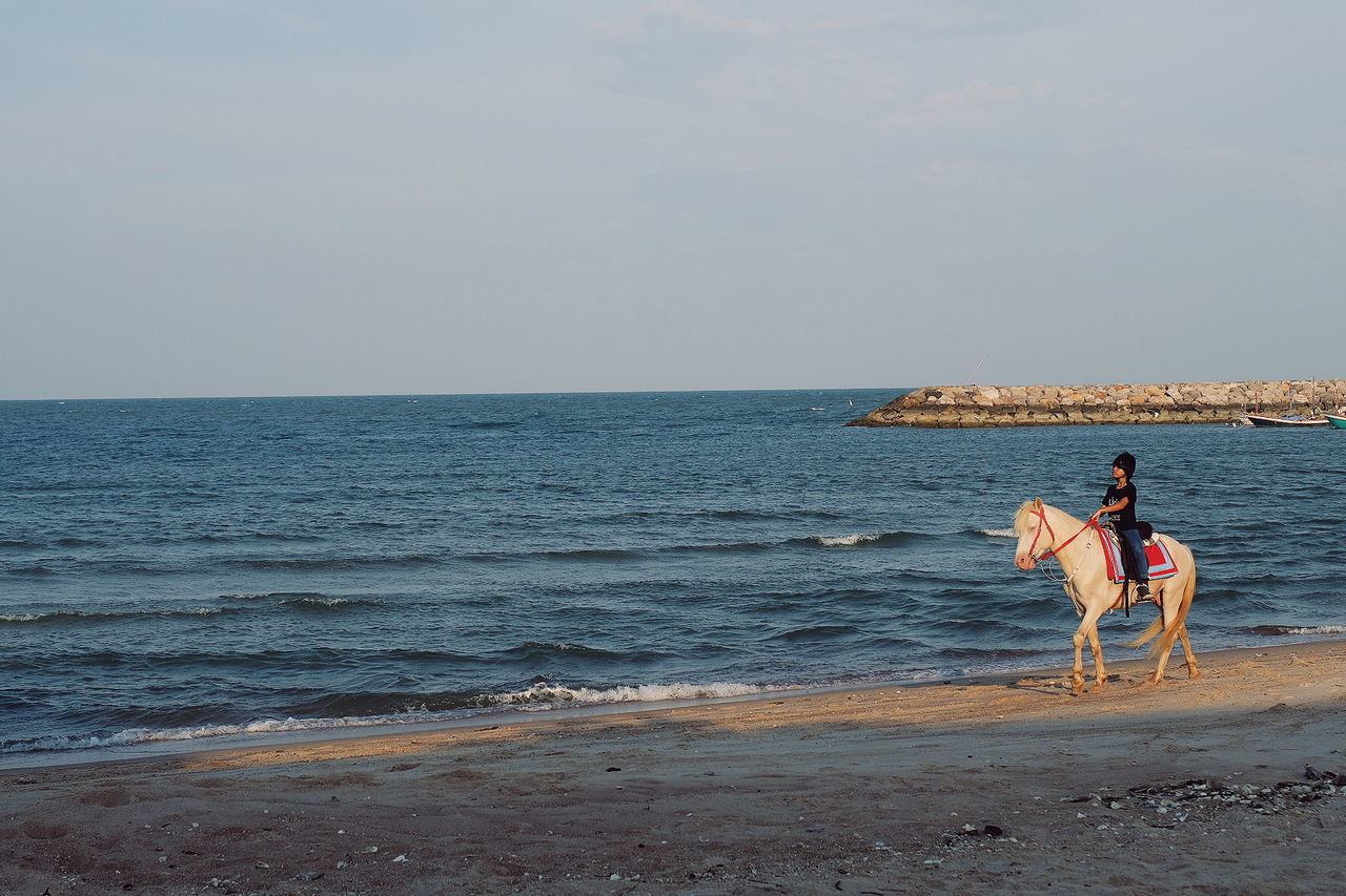 WOMAN AT BEACH AGAINST SKY