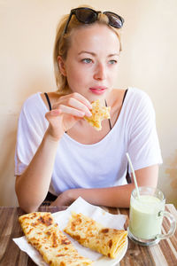 Beautiful woman eating food while sitting at restaurant