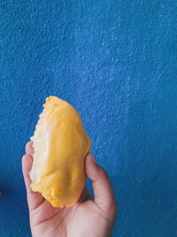 Close-up of hand holding ice cream against wall