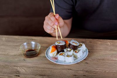 Midsection of man eating sushi