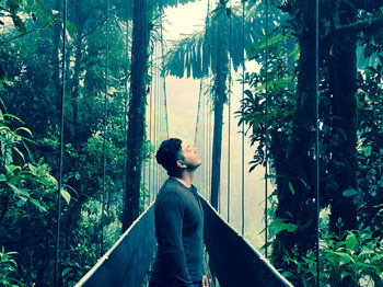 Side view of young man looking at forest