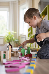 Side view of boy playing with toy at home