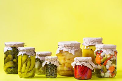 Close-up of fruits in jar against yellow background