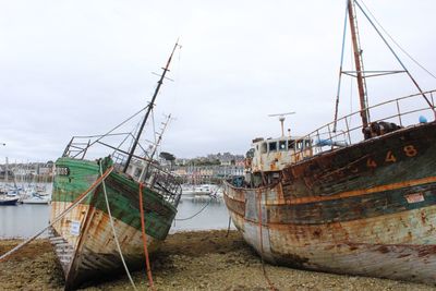 Boats moored at harbor against sky