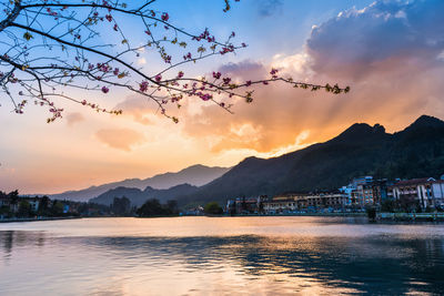 Scenic view of river by mountains against sky during sunset