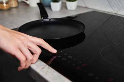 Woman hand turns on modern induction stove in the kitchen