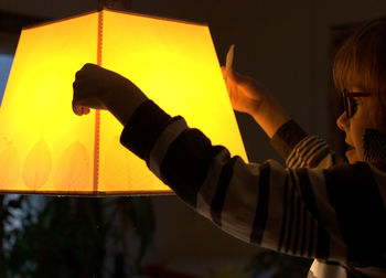 Side view of boy holding illuminated lamp shade