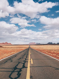 Surface level of empty road against cloudy sky