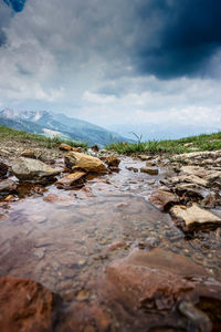 Surface level of rocks in water against sky