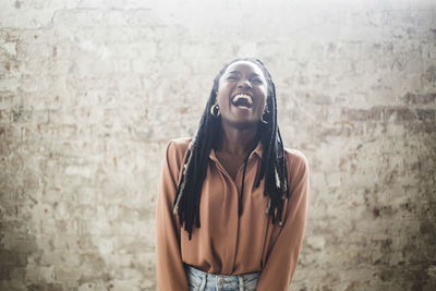 Female computer hacker with dreadlocks laughing against wall in office