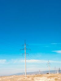 Electricity pylon on land against blue sky