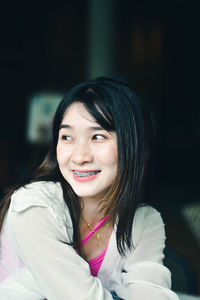 Portrait of young woman against black background