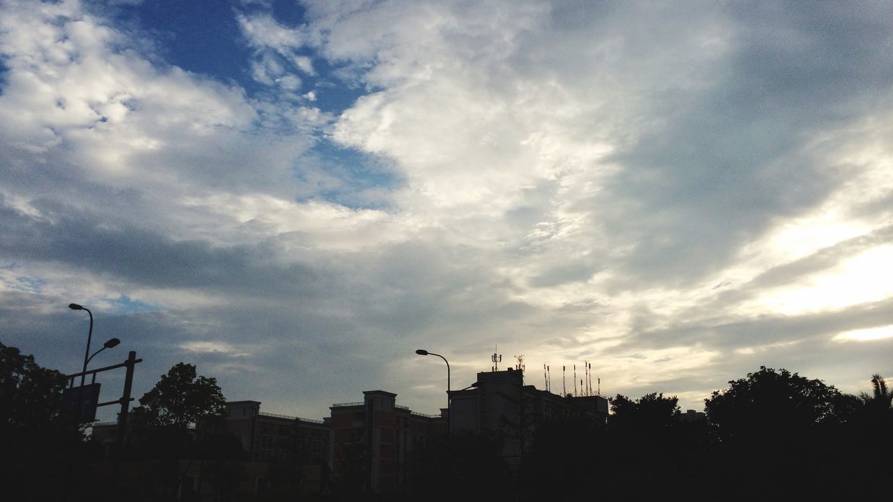 sky, silhouette, building exterior, built structure, architecture, low angle view, cloud - sky, cloudy, cloud, bird, city, animal themes, tree, sunset, flying, building, outdoors, dusk, animals in the wild, nature