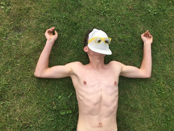 View of a young man laying on grass with hat covering face