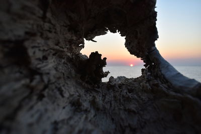 Rock formation on beach against sky during sunset