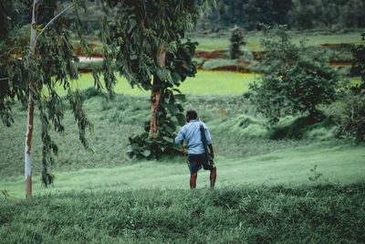 Rear view of man walking on field