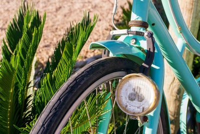 Front wheel of an old turquoise bicycle with one headlight close up