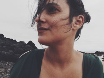 Close-up portrait of young woman standing against sky