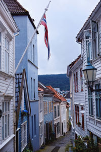 Low angle view of flags hanging amidst buildings against sky