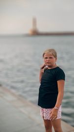 Portrait of young woman standing by sea against sky