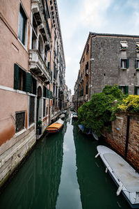 Canal amidst buildings in city against sky