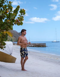 Shirtless man standing at beach