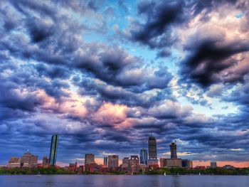 Buildings in city against dramatic sky