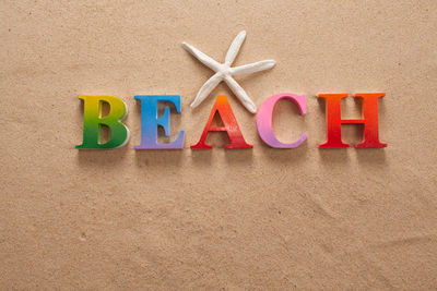 Directly above shot of beach text with seashells on sand at beach