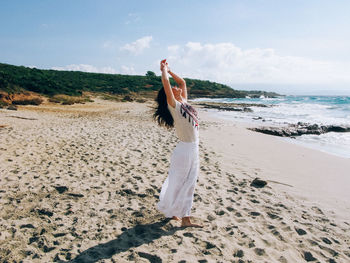 Woman standing on beach against sky