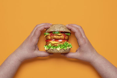 Top view with woman hands holding a vegan cheeseburger. homemade burger with plant-based ingredients