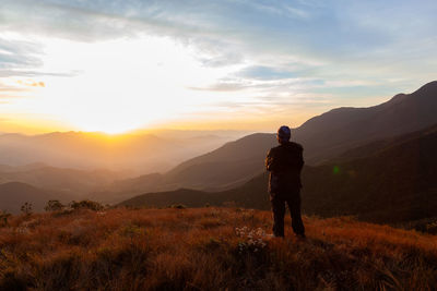 Man standing on mountain against sky during sunset