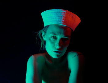 Portrait of young woman against black background