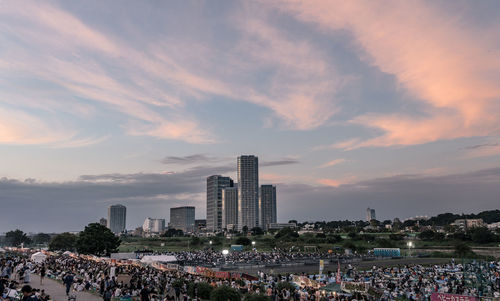 Group of people in city against sky during sunset