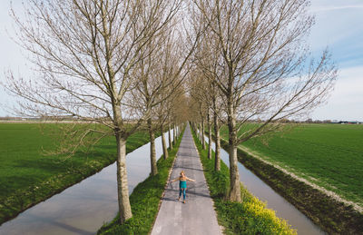 Rear view of man walking on footpath amidst bare trees