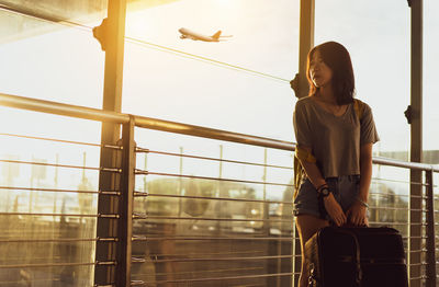 Young woman looking through window against sky