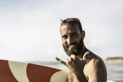 Portrait of smiling man gesturing at beach