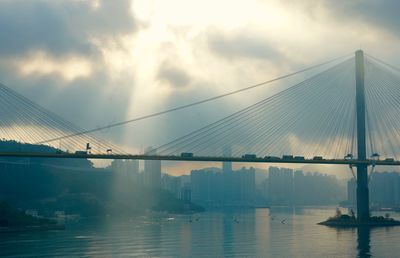 Bridge over calm river against cloudy sky