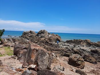 Rock formations on shore against blue sky