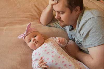 Portrait of baby lying by father on bed