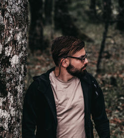 Young man looking away in forest