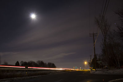 Light trails on road against sky at night