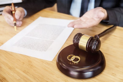 High angle view of rings over gavel by lawyer gesturing by papers on table