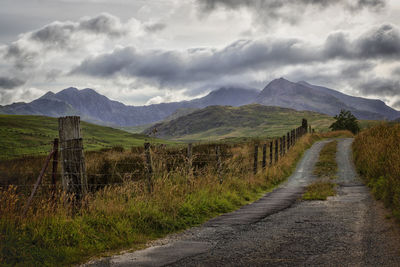 Road leading towards mountains against sky