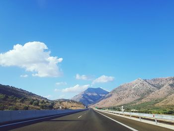 Road passing through mountains against blue sky