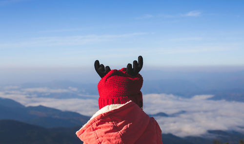 Girl in warm clothing against blue sky during winter