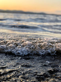 Surface level of sea against sky during sunset