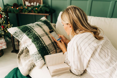 Back view of business woman at home focused on smartphone and looking for online trade. 