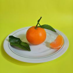 High angle view of fruits in plate against yellow background